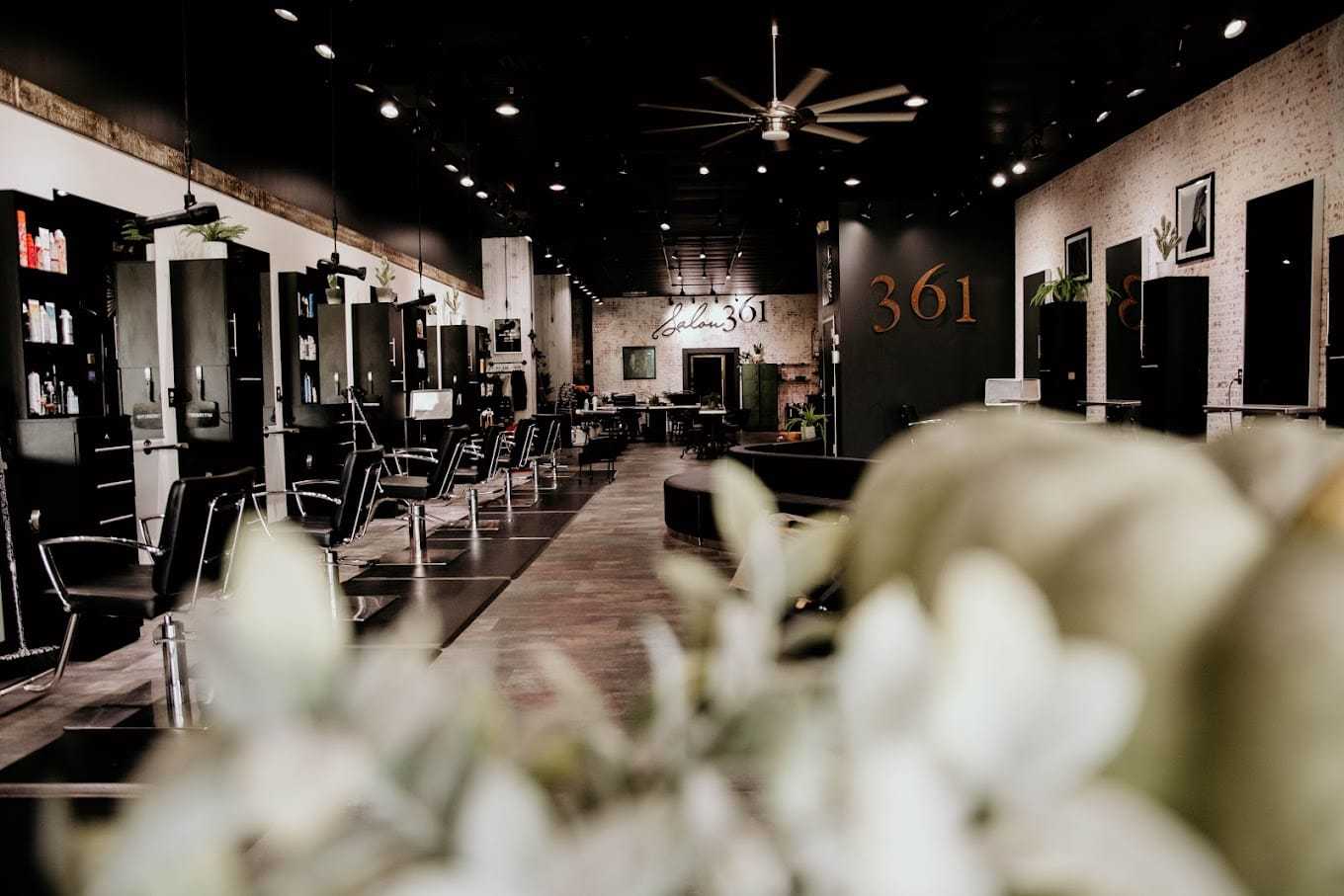 Modern hair salon interior with black chairs, mirrors, and stylish decor.