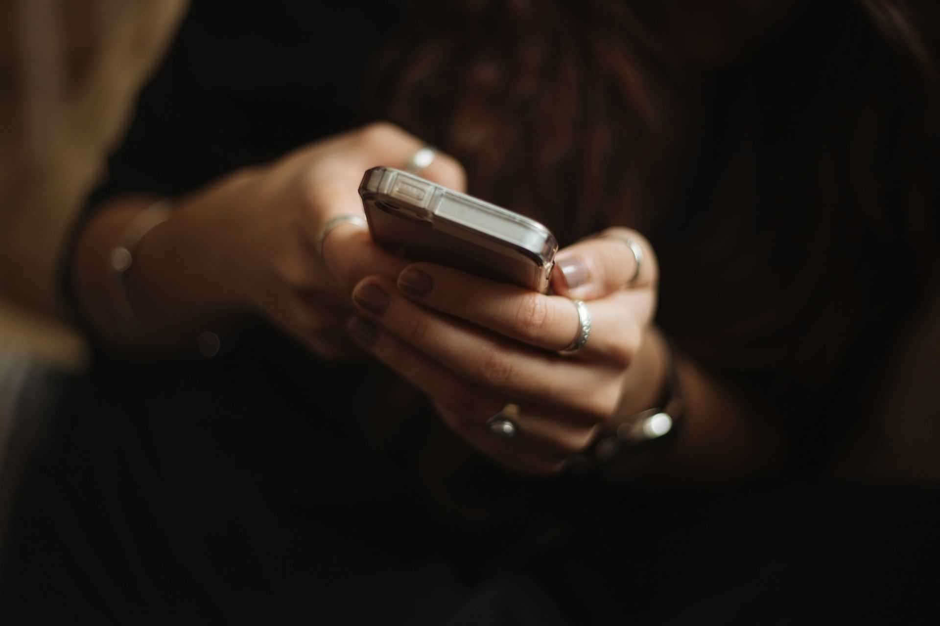 A person holding a smartphone, focusing on the screen with both hands.