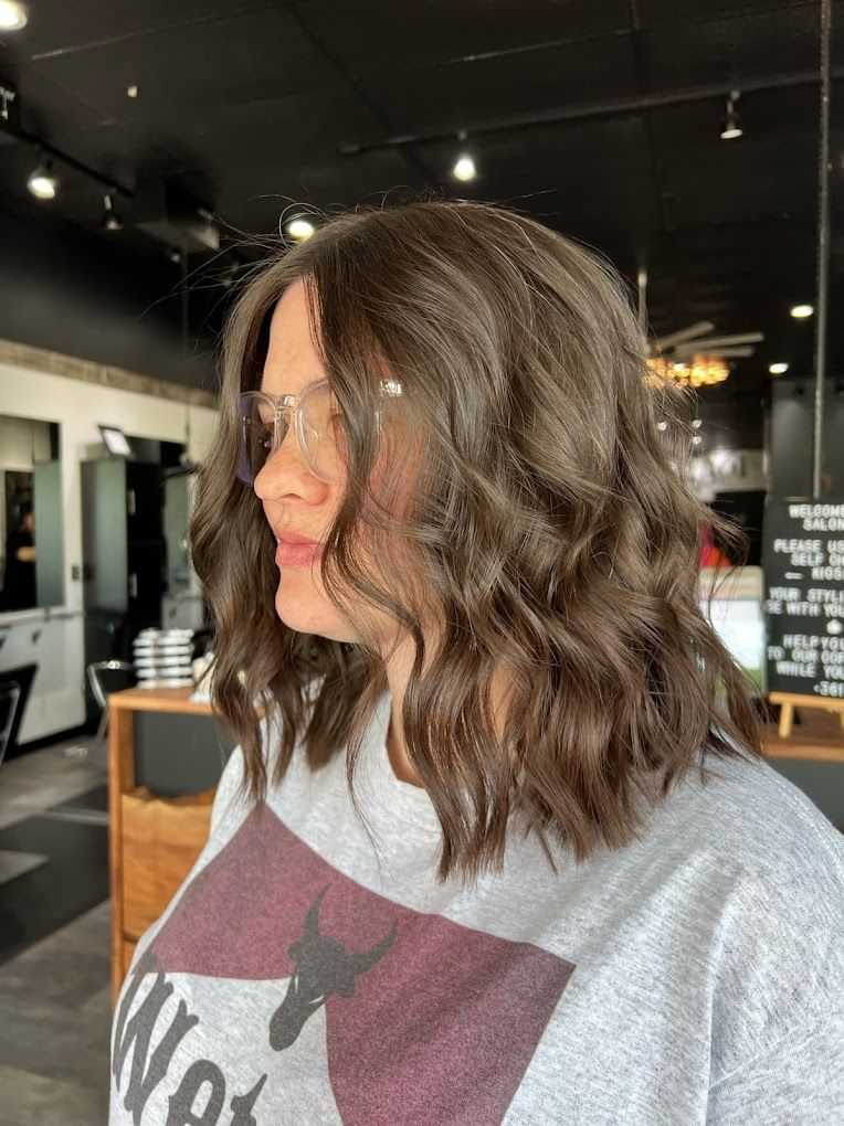 Wavy brown shoulder-length hairstyle in a modern salon setting.