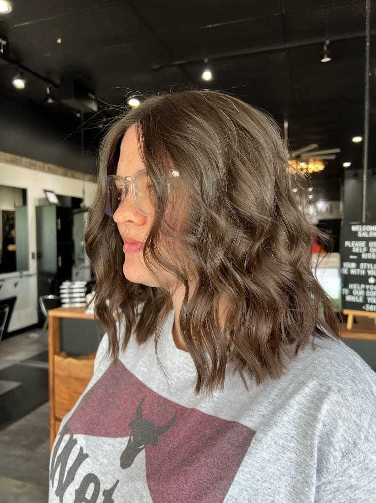 Wavy brown shoulder-length hairstyle in a modern salon setting.