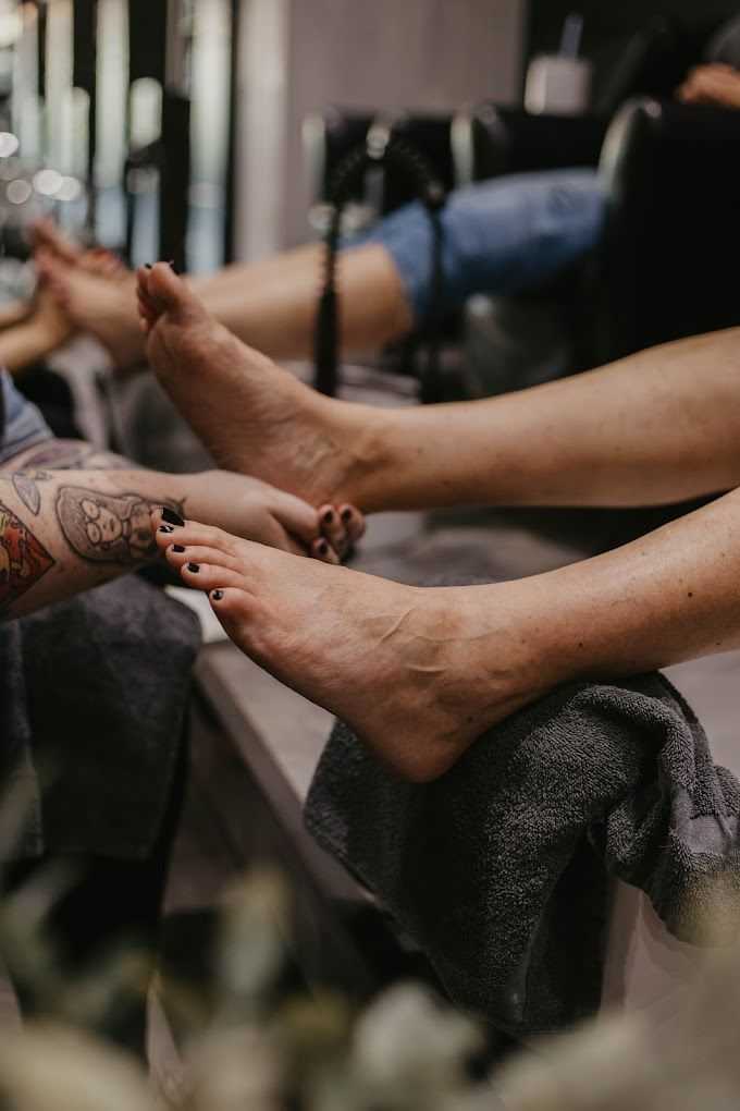 Person receiving a pedicure at a nail salon, with feet on a towel.